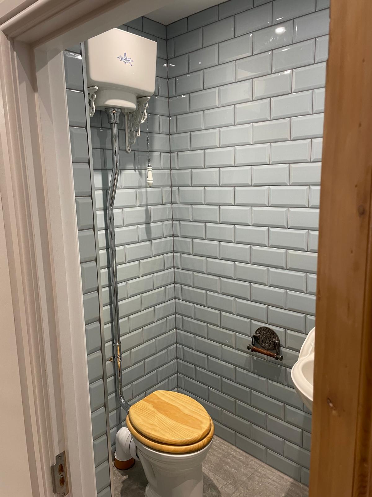 Bathroom renovation with toilet and grey tiled wall